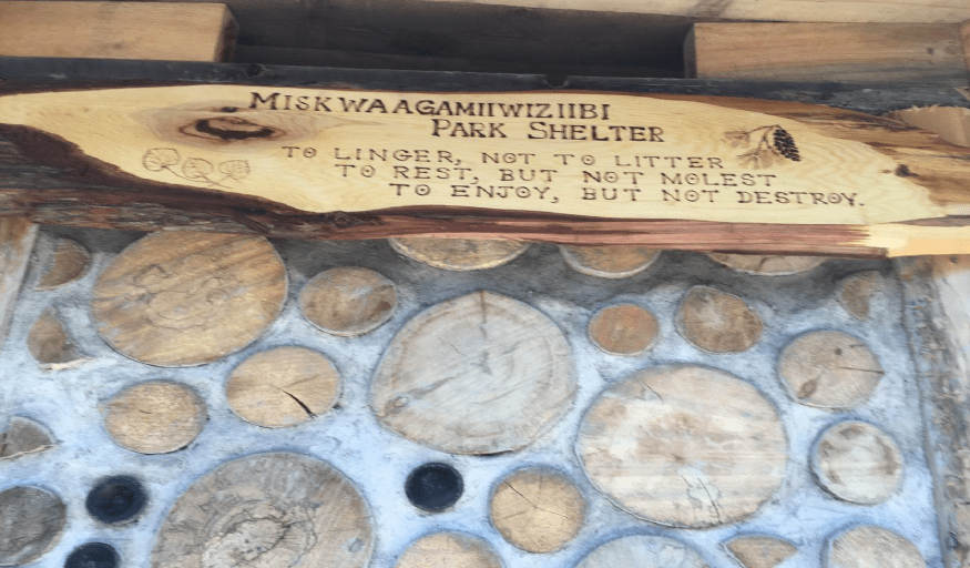 Wood burned park sign attached to shelter